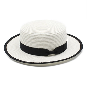 Detailed view of woven straw hat featuring black ribbon trim and elegant bow detail