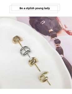 Detail of four minimalist gold and silver metal hair hooks arranged on a ceramic tray