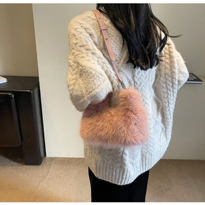 Detail of pink plush crossbody bag with leather strap worn by a model in a modern interior