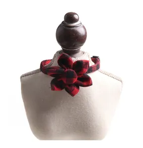Detail of red and black buffalo plaid fabric flower collar for pets on a white display stand