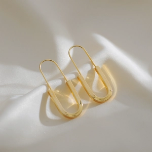 Minimalist gold safety pin earrings in 18K gold plated titanium steel on white silk
