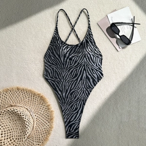 Close-up of zebra print one-piece swimsuit with cross-back straps on beach mat