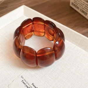 Macro detail of amber resin bangle with wavy marble texture on a textured fabric