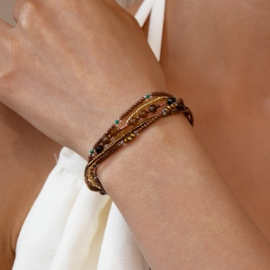 Detail van een gelaagde bohemian kralenarmband met koffiekleurige en gouden kralen