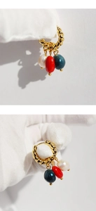 Macro detail of gold twisted hoop earrings with pearl and colorful stone bead pendants