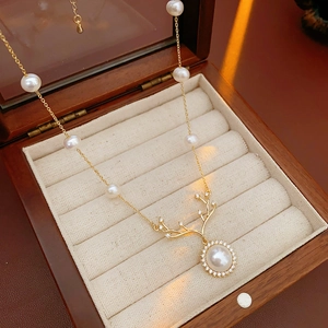 Dettaglio della collana corna di cervo dorata con perle e zirconi in scatola di legno