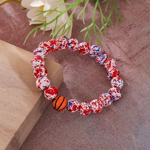 Macro detail of red, white, and blue beaded bracelet with basketball charm on wood