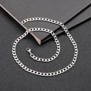 Macro view of silver stainless steel Cuban link chain with lobster clasp on black background