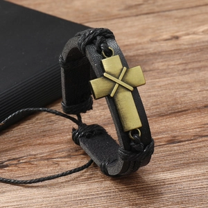 Detail of vintage braided black leather bracelet featuring a bronze alloy cross charm