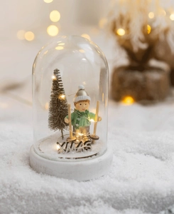 Detail of a Christmas glass dome with a skiing figure, mini tree, and LED XMAS lights
