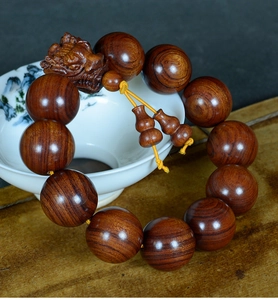 Détail macro des perles en bois de Huanghuali avec tête de dragon sur porcelaine blanche