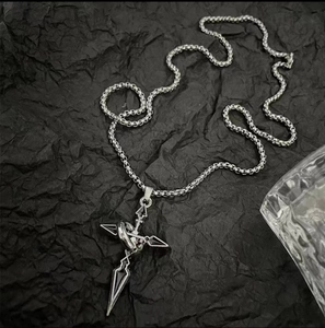 Détail du collier chaîne à mailles avec pendentif croix tribal sur papier noir