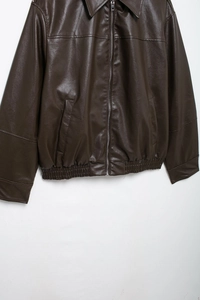 Detailed close-up of dark brown faux leather aviator jacket texture and metal zipper