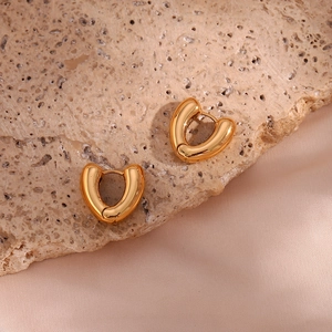Detail shot of heart-shaped gold-plated stainless steel earrings on silk and stone