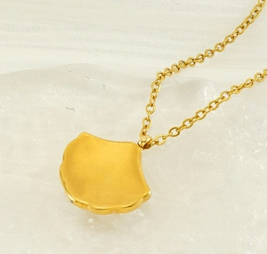 Detailed close-up of a golden fan-shaped necklace pendant with frosted metal texture