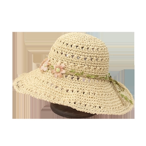 Beige hollow straw sun hat with pink floral decor and wide brim for summer beach protection
