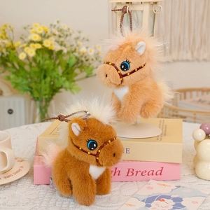 Detail of plush pony charms with large embroidered eyes on decorative book stack