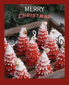 Close-up of red and white Christmas tree candles with small gold bells on wooden tray