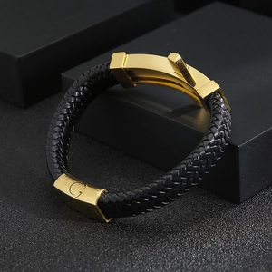 Detail of black braided leather bracelet with golden G-logo magnetic clasp and premium finish