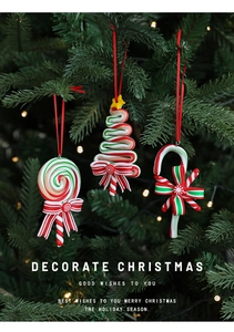 Close-up of red and green clay candy cane and lollipop ornaments on a Christmas tree