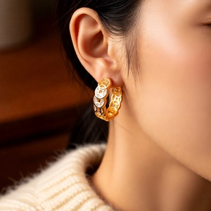 Detail of 18K gold-plated copper coin hoop earring worn on a model's ear