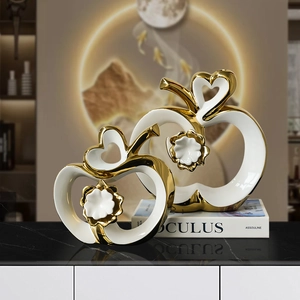 Modern ceramic apple decor set with hollow heart and gold trim on marble tabletop