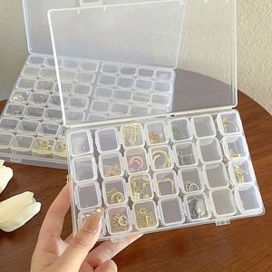 Close-up of a clear plastic jewelry organizer with multiple grids and a hinged lid