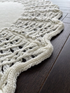 Detail of cream knit Christmas tree skirt featuring intricate lace hollow wavy edges
