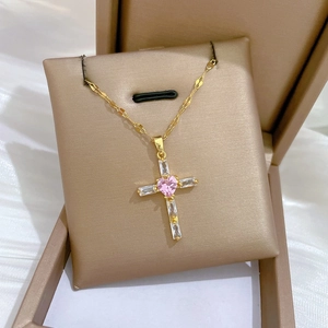 Macro shot of pink heart gemstone cross necklace on luxury champagne jewelry box pillow
