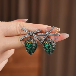 Macro view of vintage style bow earrings with green and yellow zircons in black gold