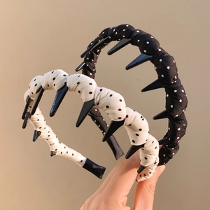 Handheld view of black and beige polka dot wavy hairbands with plastic gripping teeth