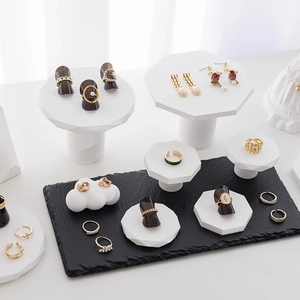 Minimalist white plaster jewelry display stand set with gold rings on marble base