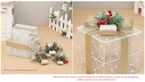 Detail of white lighted Christmas gift boxes with golden bows and pinecone accents