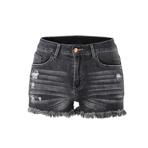 Dettaglio dell'orlo strappato e del tessuto denim nero sui pantaloncini a vita bassa da donna
