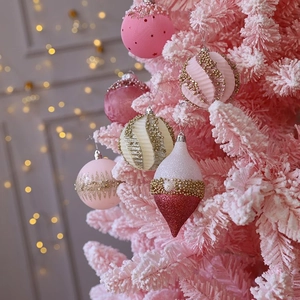 Boules de Noël roses et blanches avec paillettes dorées sur une branche de sapin floquée