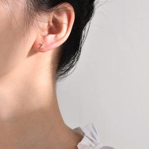 Close-up of minimalist gold letter Z stud earring with zircon stones on female ear