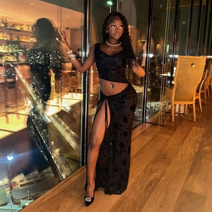 Detail of black velvet two-piece set featuring high slit skirt and mesh cropped top