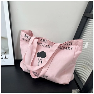 Detailed close-up of pink canvas tote bag with black floral art and letter printing