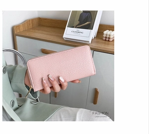 Detailed view of pink long purse with lychee texture and gold metal zipper hardware