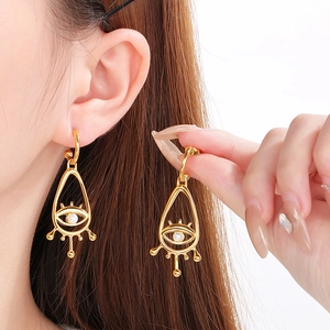 Bohemian gold evil eye drop earrings with white bead on a model's ear in minimalist style