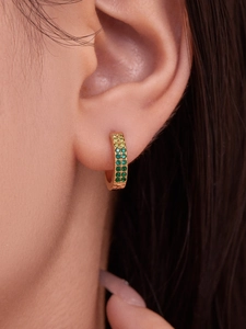 Macro shot of 18k gold-plated C-shaped huggie earrings with double-row green zircons