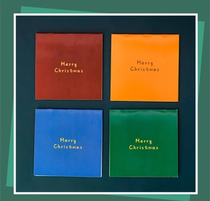 Close-up of four colorful Christmas cards with gold Merry Christmas lettering on green background