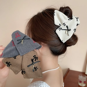 Close-up of elegant tweed bow hair clips with gold charms in grey brown and beige colors