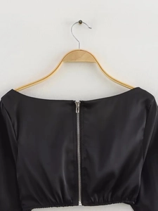 Nahaufnahme des Metallreißverschlusses am Rücken eines schwarzen Satin-Cropped-Tops für Damen