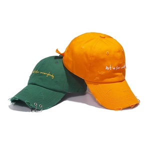 Detail of distressed baseball cap with metal rings and Art is for everybody embroidery