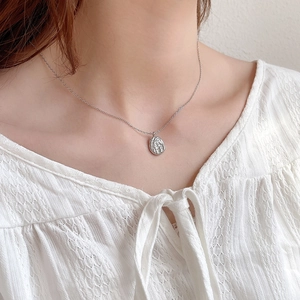 Minimalist 925 sterling silver necklace with textured irregular oval pendant on a model