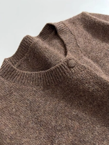 Close-up of brown knit cardigan featuring ribbed crew neck and matching fabric buttons