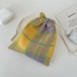 Macro detail of yellow and purple plaid cotton drawstring storage pouch on a desk