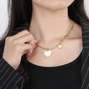Detail of layered gold snake chain necklace with white heart pendant on model