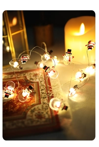 Detail of glowing snowman fairy lights with red scarves and warm LED bulbs on a cozy rug